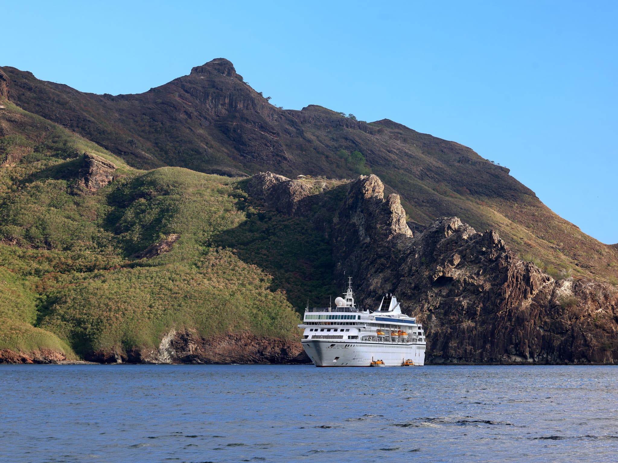 Villa Vie Odyssey anchored near dramatic mountain cliffs