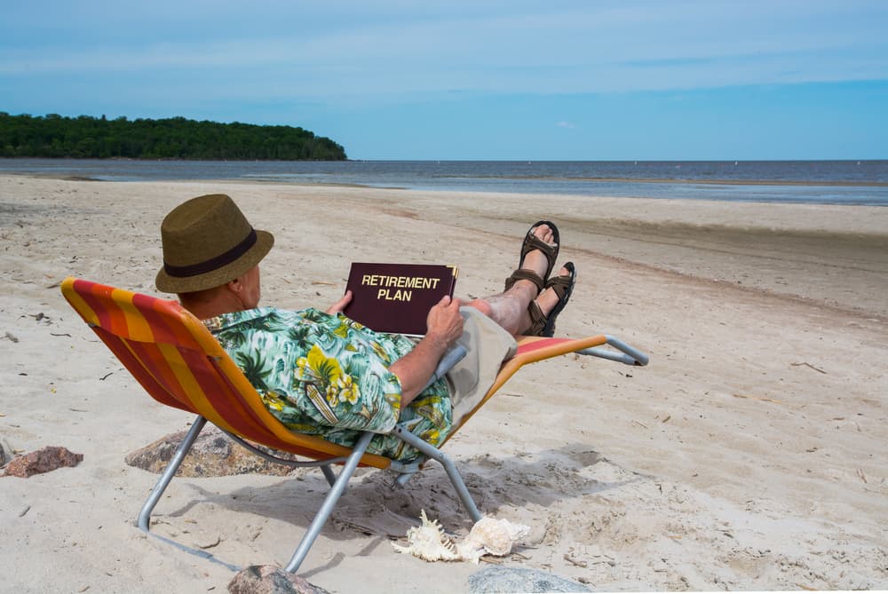 Older man relaxing on the beach with a cruise ship living retirement plan